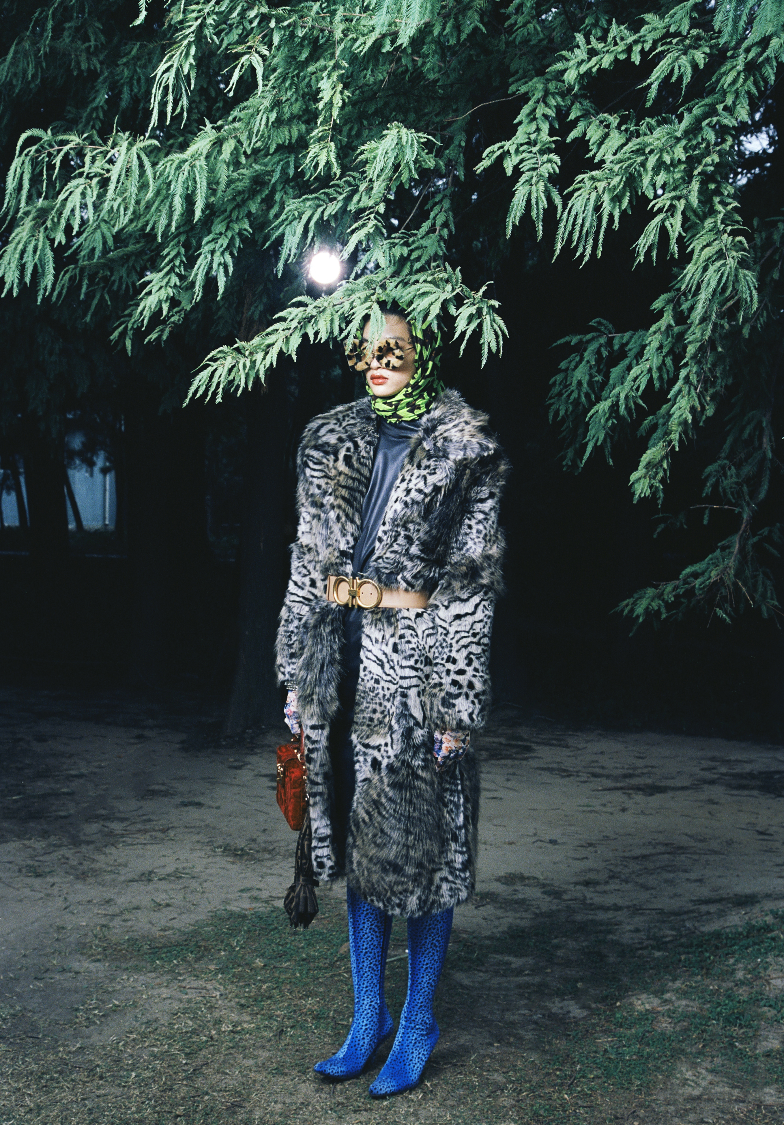 Leopard-print faux fur and red handbag by Dolce and Gabbana; Green logo scarf is vintage Louis Vuitton available at OnceStyle.hk; Animal-print faux fur coat by Stella McCartney; Navy leather dress by Hermès; Beige belt by Salvatore Ferragamo; Blue velvet leopard-print boots by Balenciaga; Bracelet by Swarovski; Grey umbrella charm by Fendi; gloves stylist's own